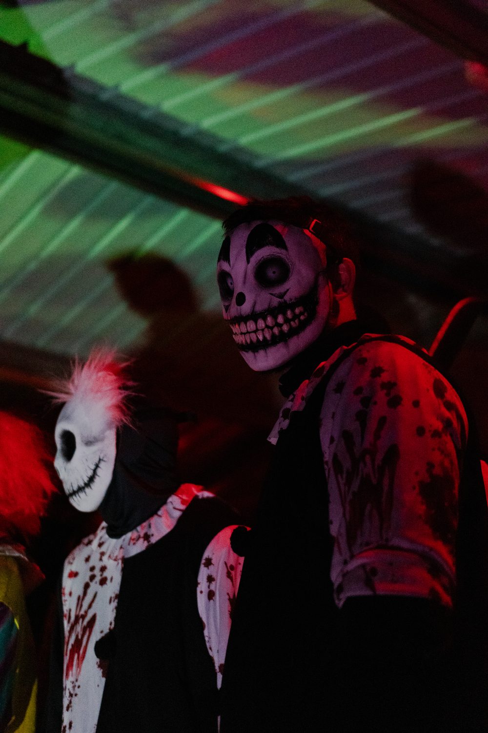 Deux personnages masqués sous lumière colorée